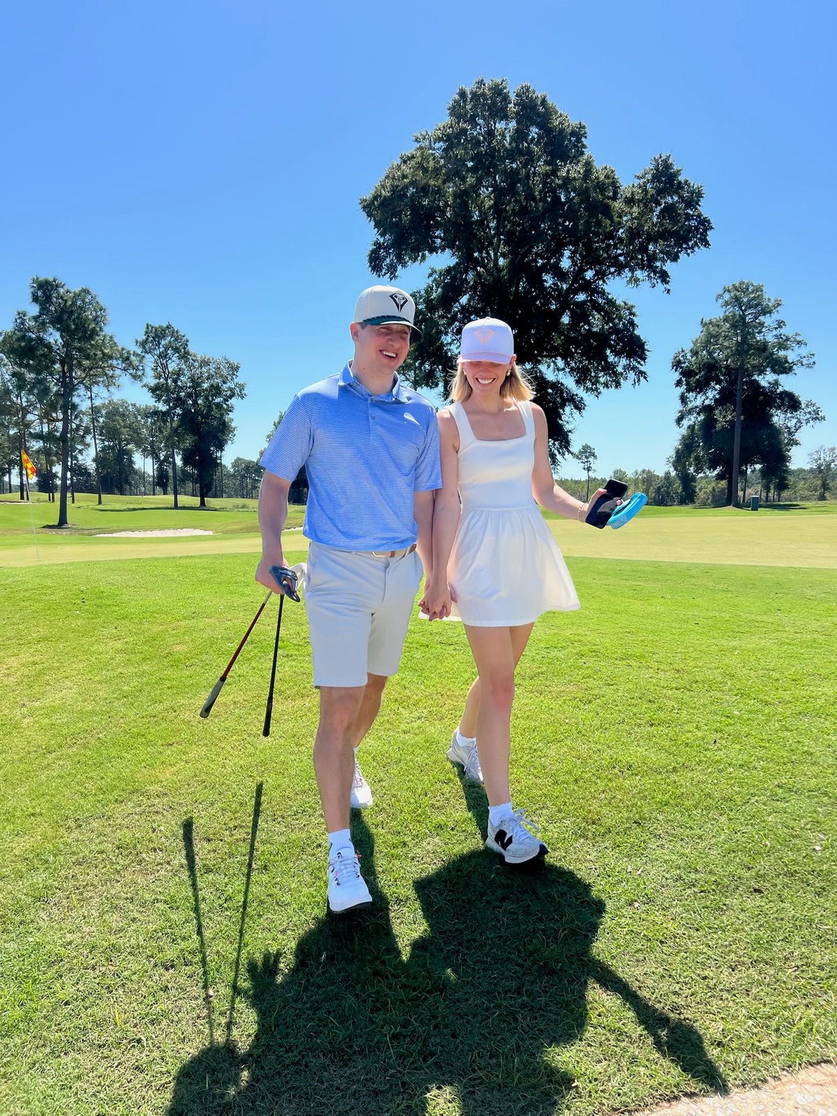 Couple in La Vita rope hats walking hand in hand on the golf course