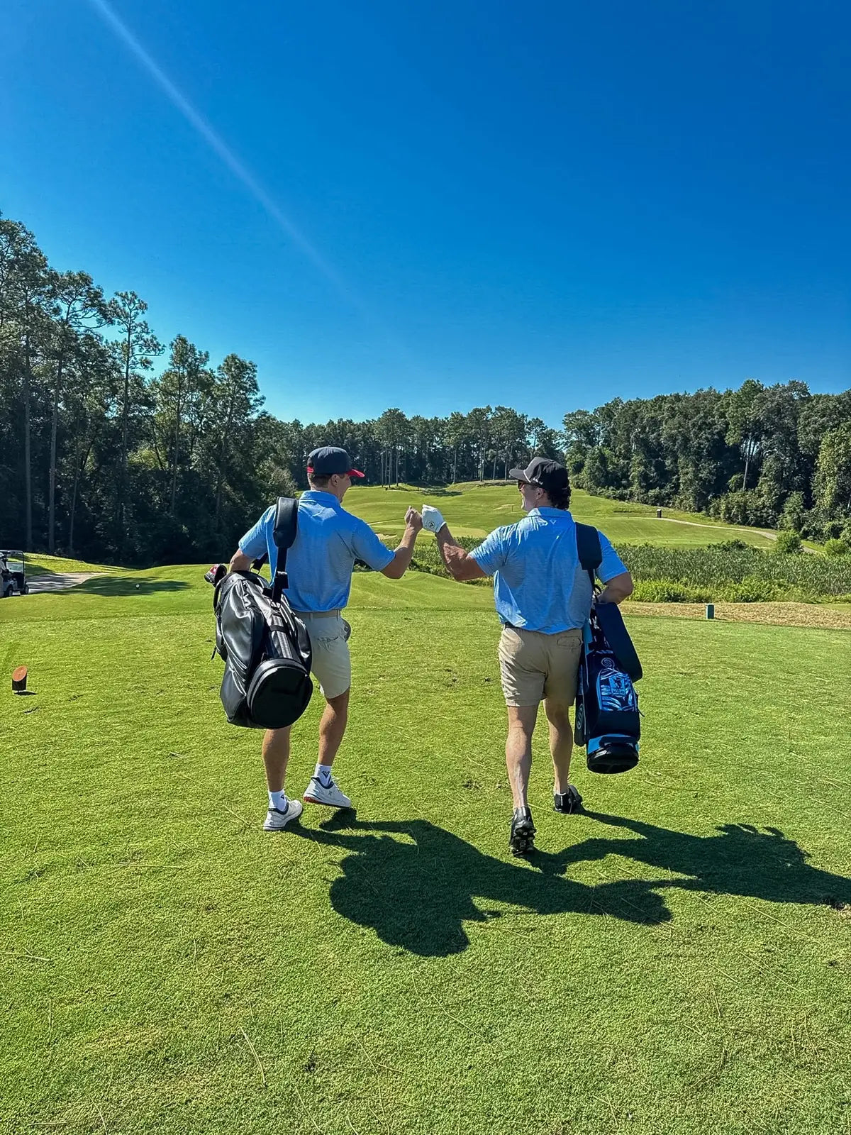 Two golfers bumping fists as they walk the fairway